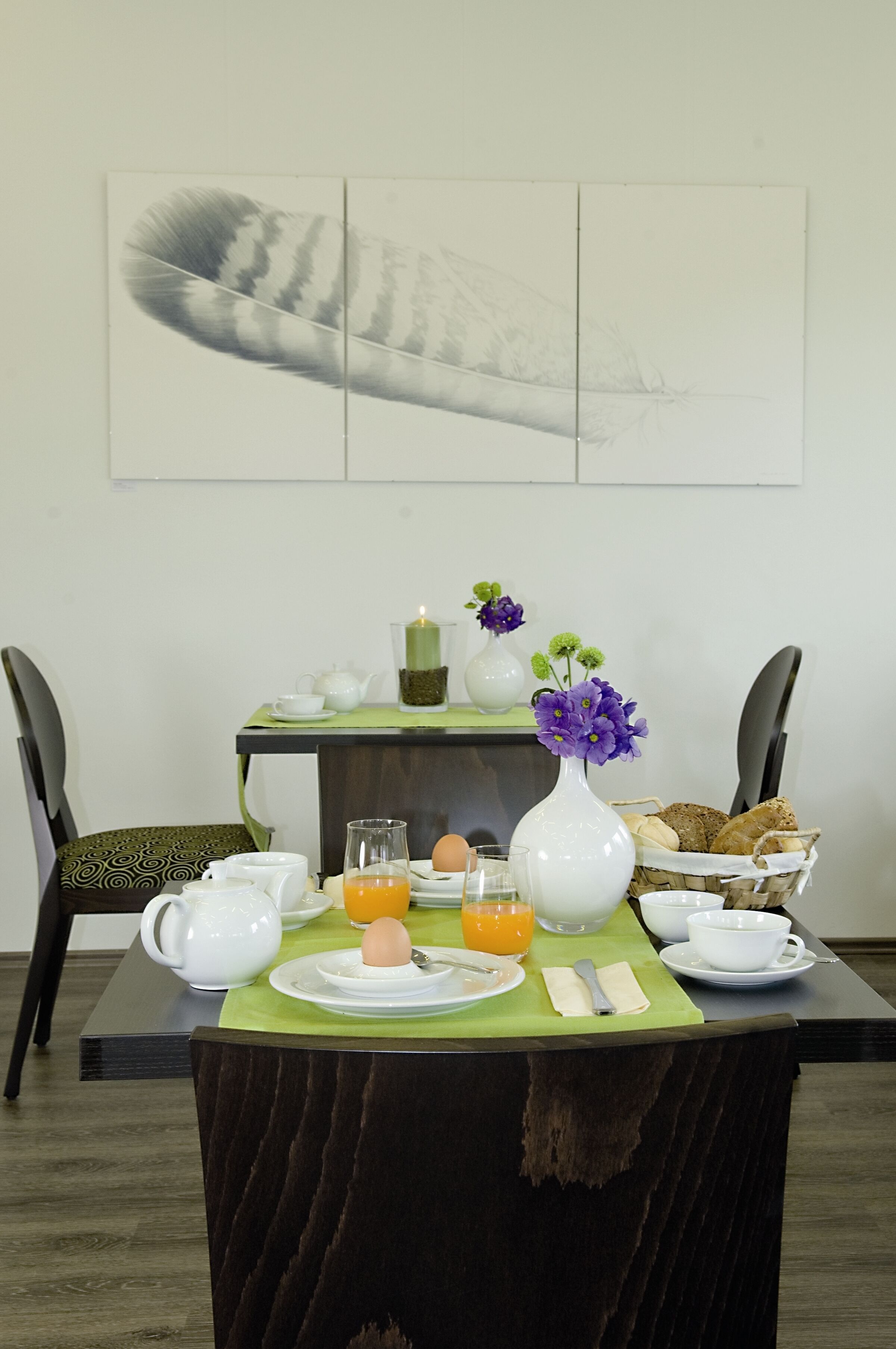 A breakfast table set with plates, cups, and a vase of flowers.