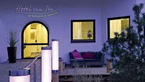 Een hotelgevel in paars, een houten trap, een zithoek met kussens en een potplant.