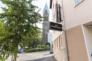 Et hotel, der hedder "HOTEL am Friedensplatz", med et synligt tårn med et ur i baggrunden.