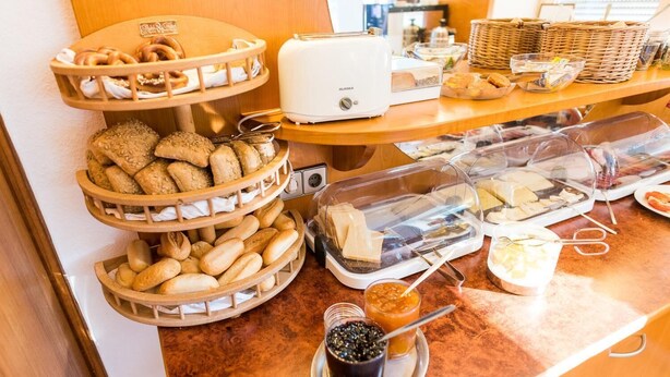 A buffet setup with various bread and pastries, a toaster, and condiments. - Hotel Am Friedensplatz (Stuttgart)