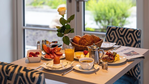 Una mesa de desayuno con diversos alimentos, una cafetera y un periódico.