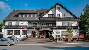 Un edificio de dos pisos con un balcón, un letrero que dice “Hotel Schneider” y una bandera.