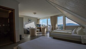 Habitación de hotel con una cama grande, un escritorio con una computadora, una silla y vistas al exterior.