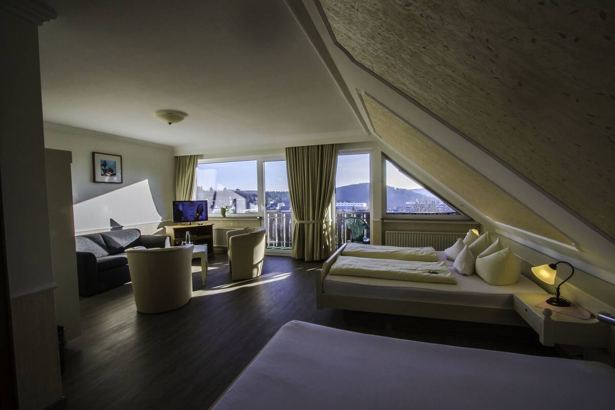 A hotel room with a bed, a desk, a chair, and a view of the city.