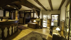 Una habitación acogedora con vigas de madera, un escritorio de madera, un sofá y una lámpara.