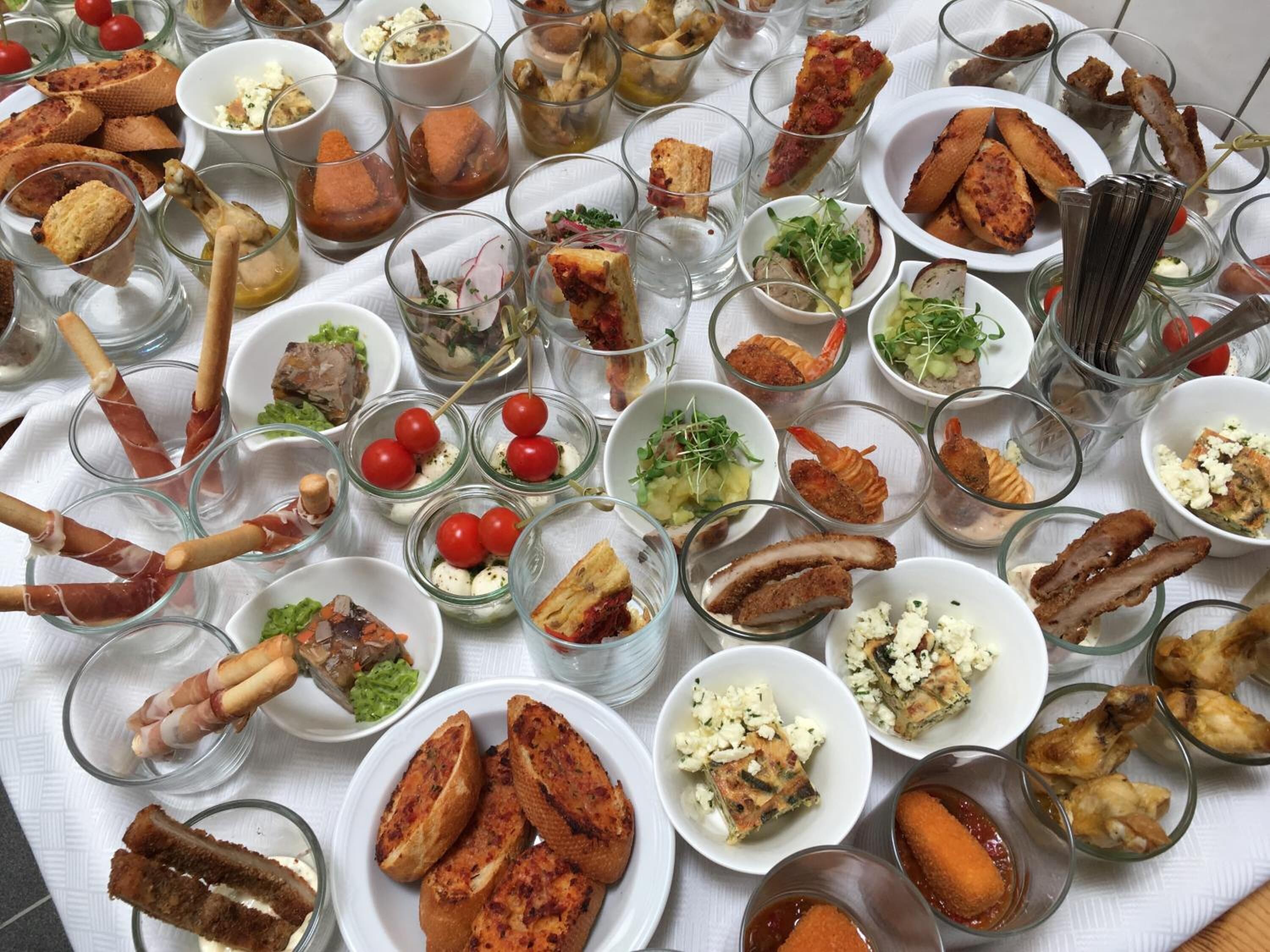 Une table sur laquelle sont disposés divers aliments et boissons, notamment de petits bols, des assiettes et des verres.