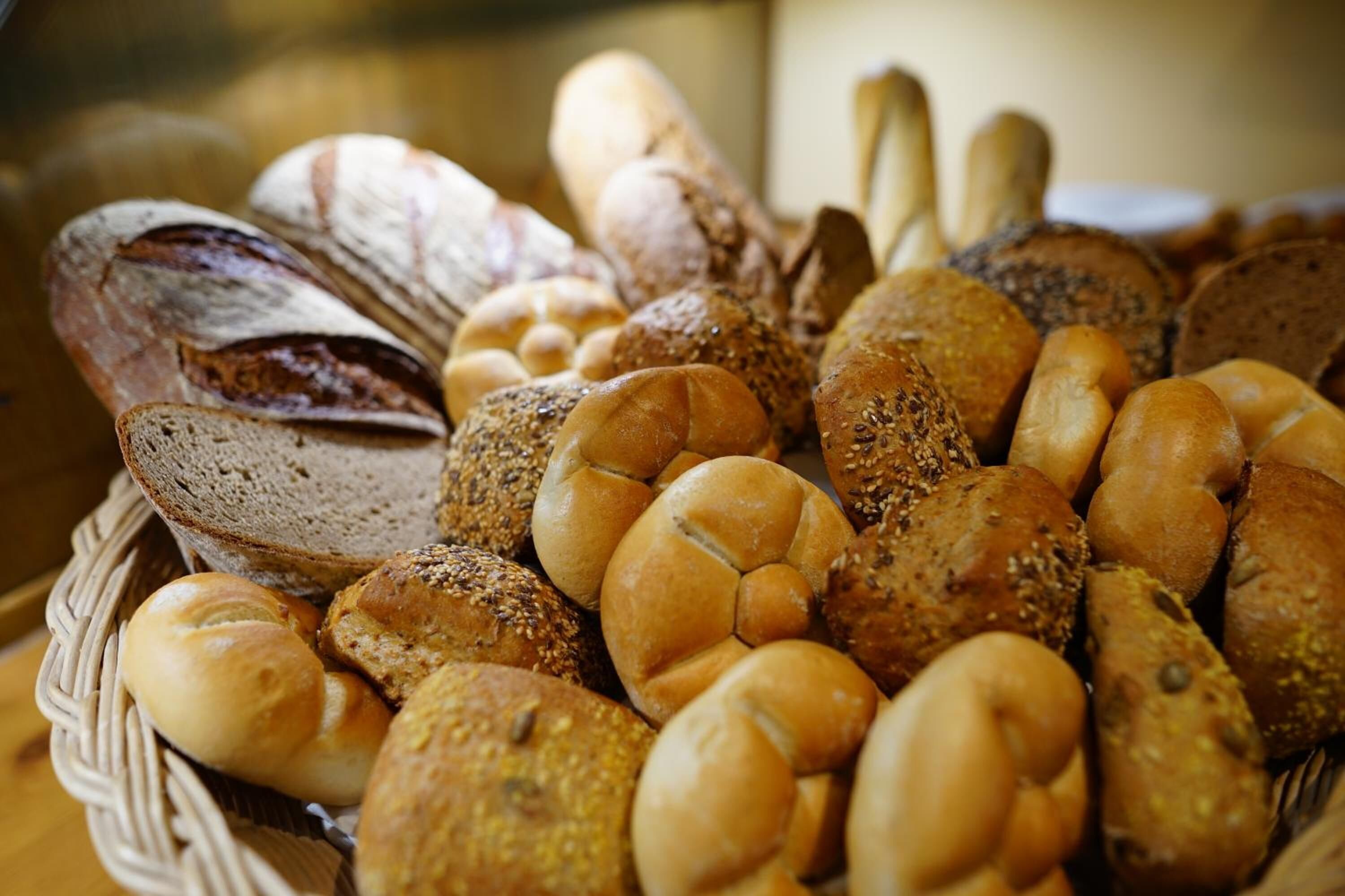 A basket filled with various types of bread, including loaves and rolls.