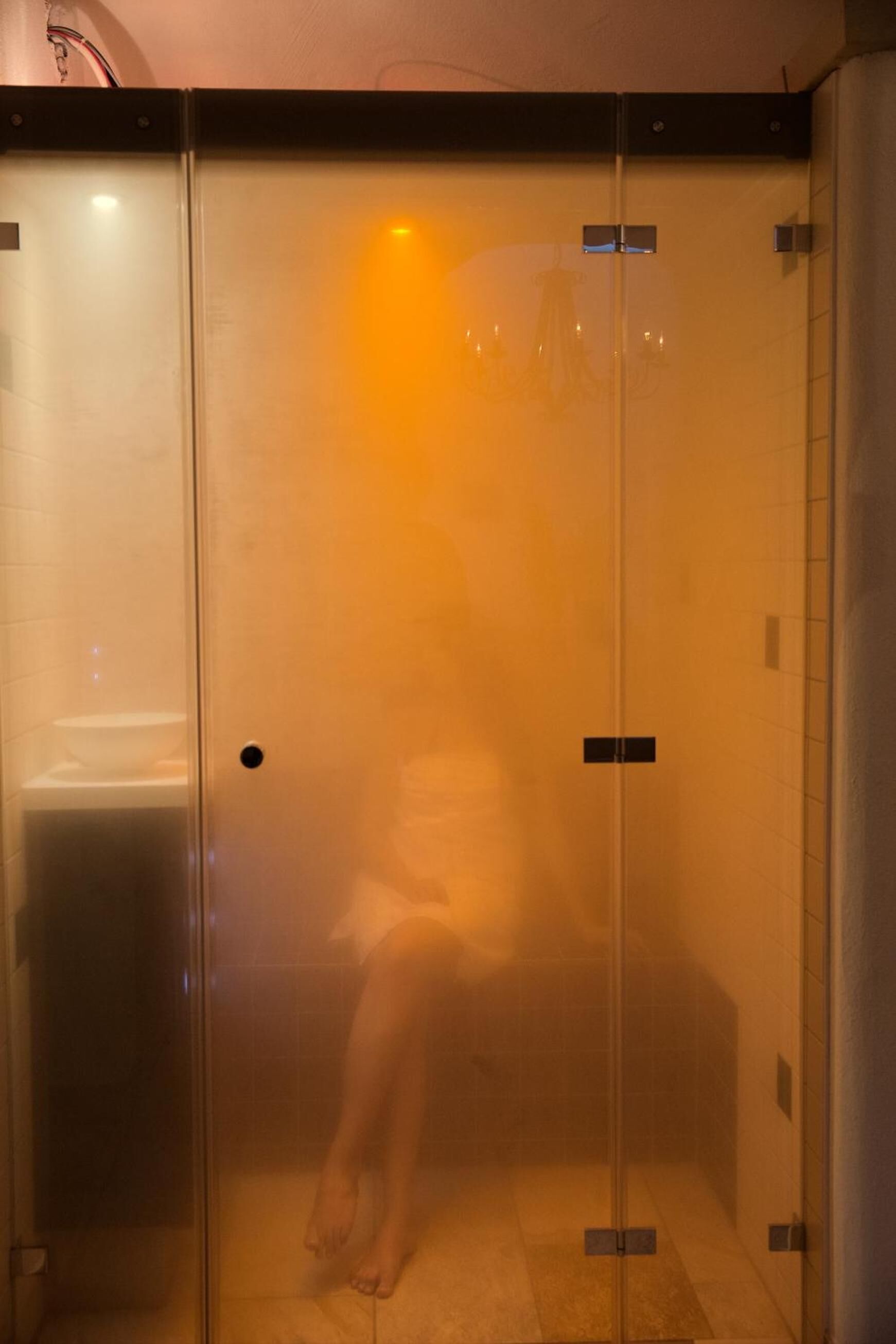A glass-enclosed elevator with a person inside, a tiled floor, and a visible handrail.