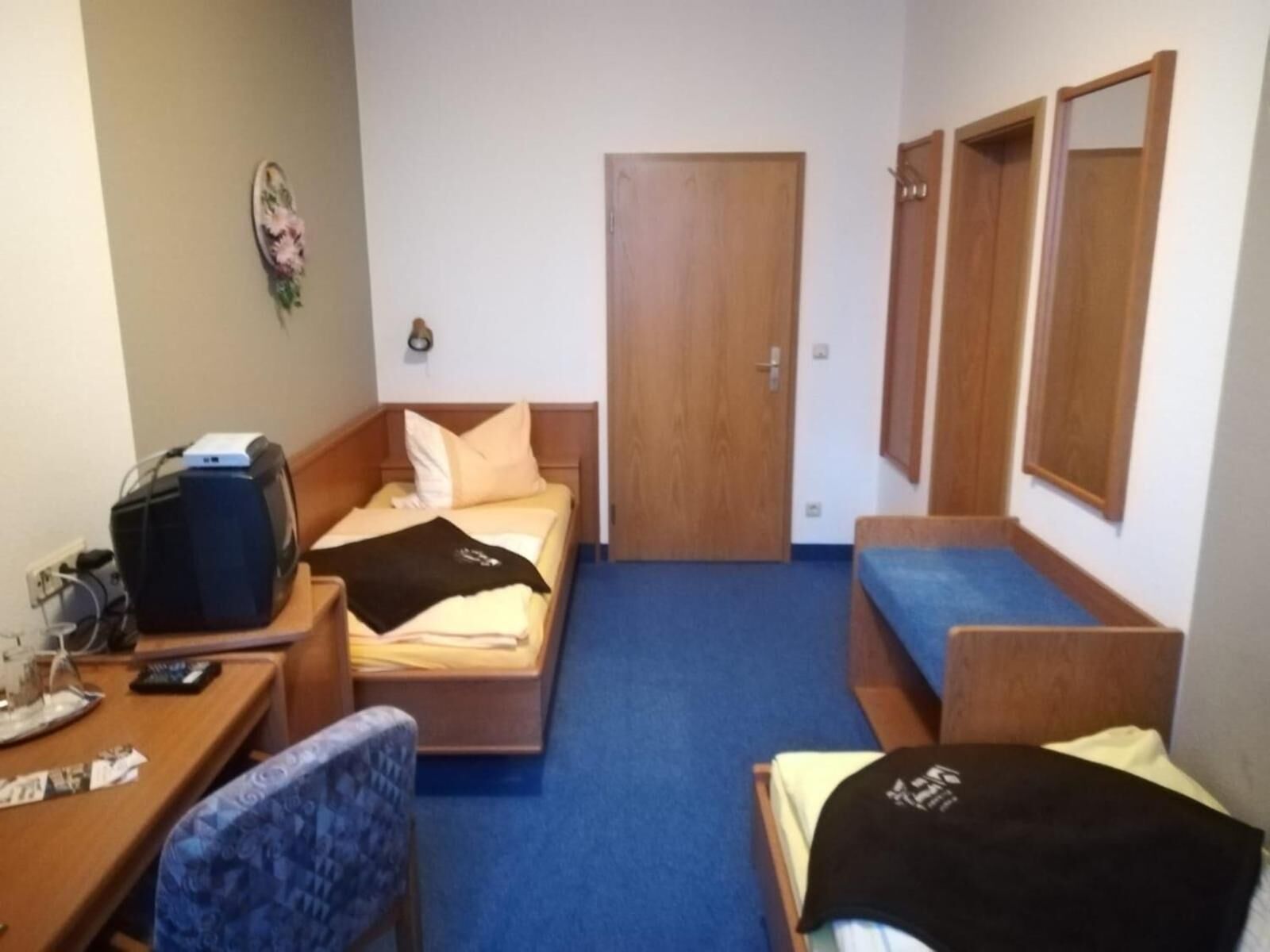 A small hotel room with a bed, a desk with a computer, a chair, and a sofa.