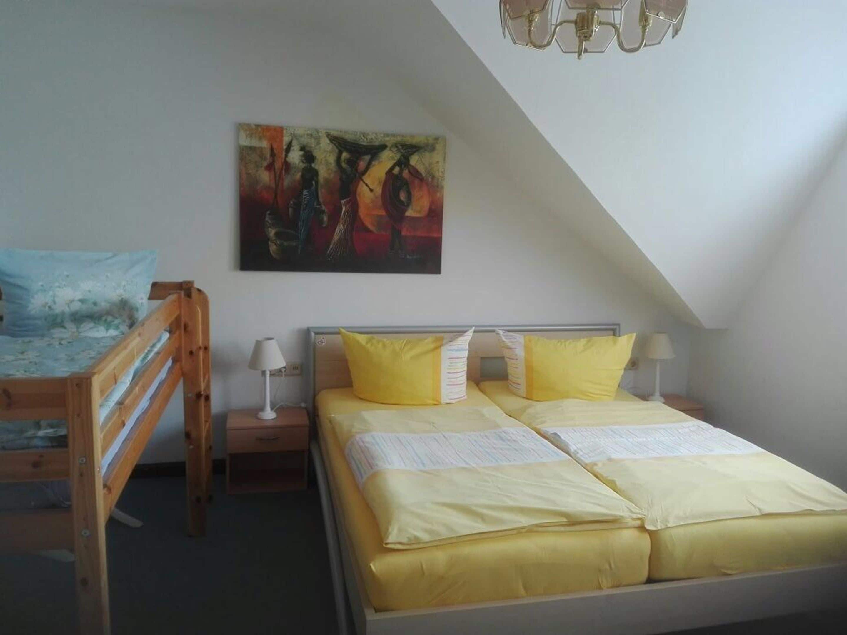 A room with a bunk bed, a desk, and a painting on the wall.