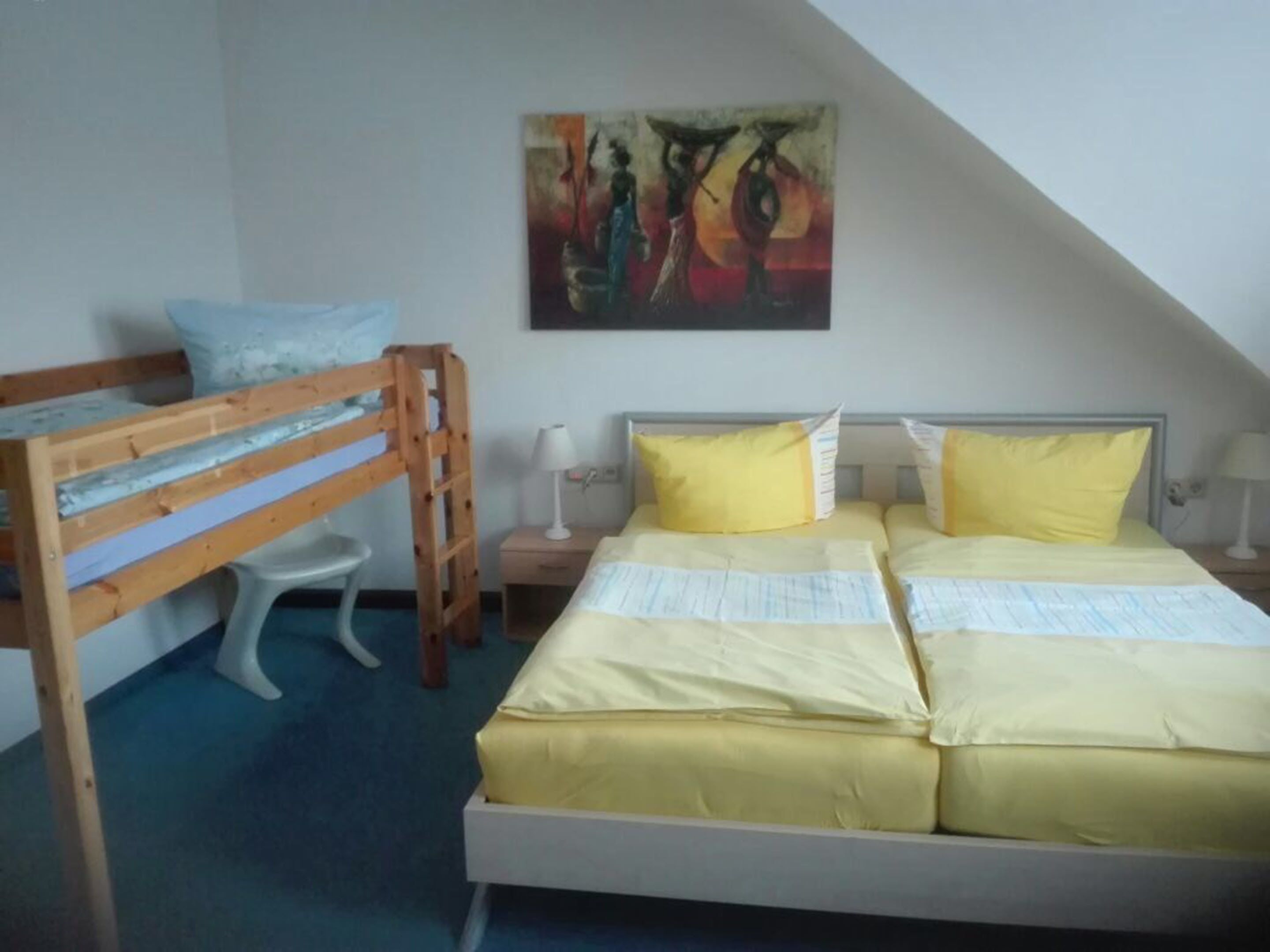 A room with a bunk bed, a desk with a lamp, and a painting on the wall.