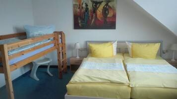 A room with a bunk bed, a desk with a lamp, and a painting on the wall.
