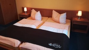 Een tweepersoonsbed met een zwart hoofdeinde, twee nachtkastjes met lampen, en een bloemendecoratie aan de muur.