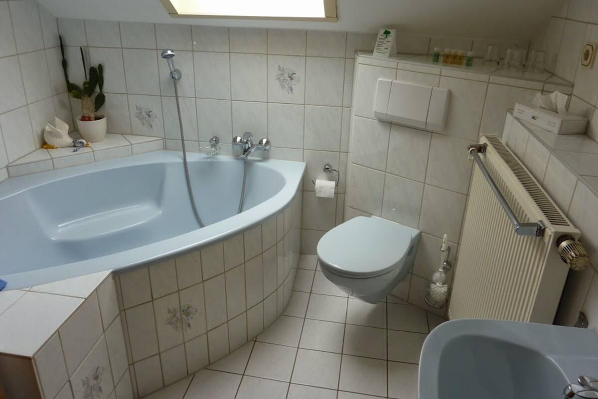 Ein Badezimmer mit einer großen Badewanne, einer Toilette und einem Heizkörper.