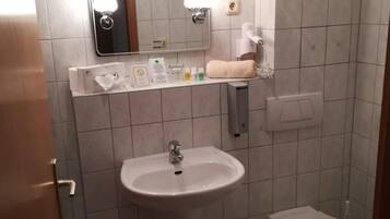 A small bathroom with a sink, toilet, and a mirror.