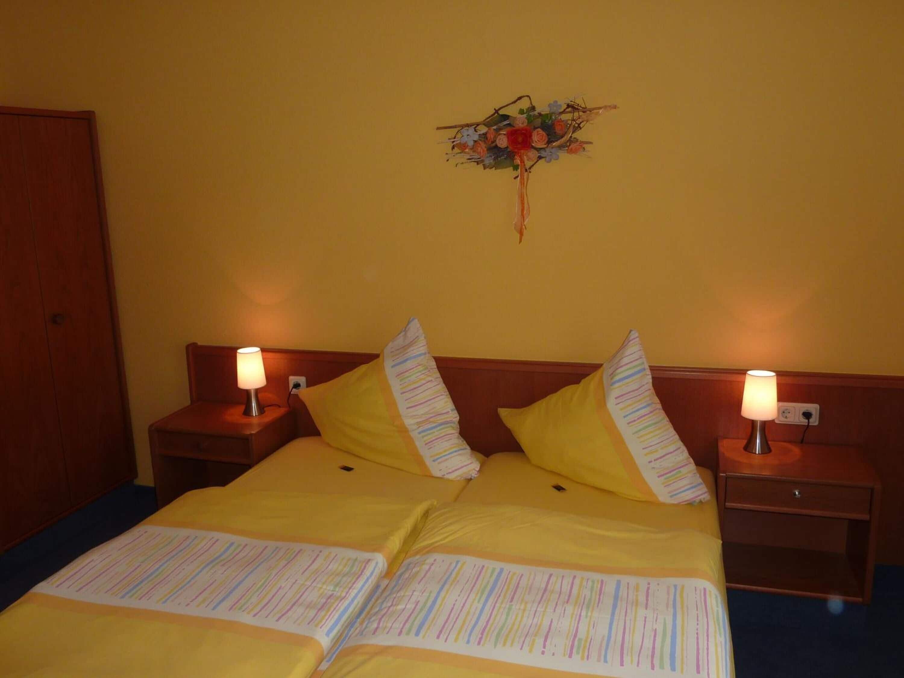 Une chambre d’hôtel avec un lit, deux tables de chevet et un élément décoratif mural.