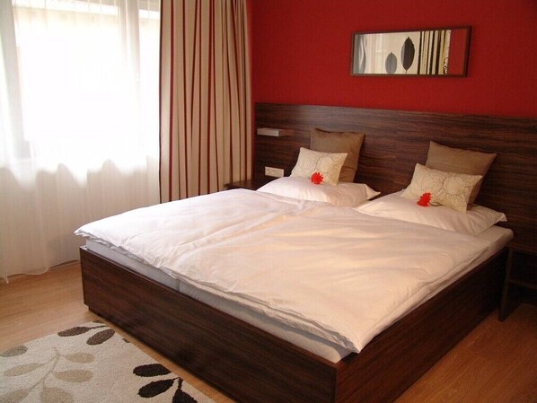 A double bed with white linens, a wooden headboard, and a red accent wall. - Landhotel Wolfschlugen (Wolfschlugen)