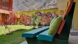 A building with a colorful mural, a red staircase, and a view of mountains. - Pisac Inca Guest House - Hostel (Pisac)