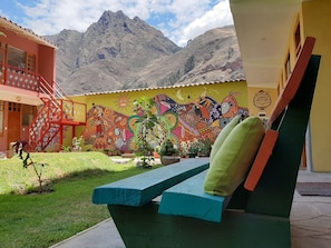 A building with a colorful mural, a red staircase, and a view of mountains. - Pisac Inca Guest House - Hostel (Pisac)