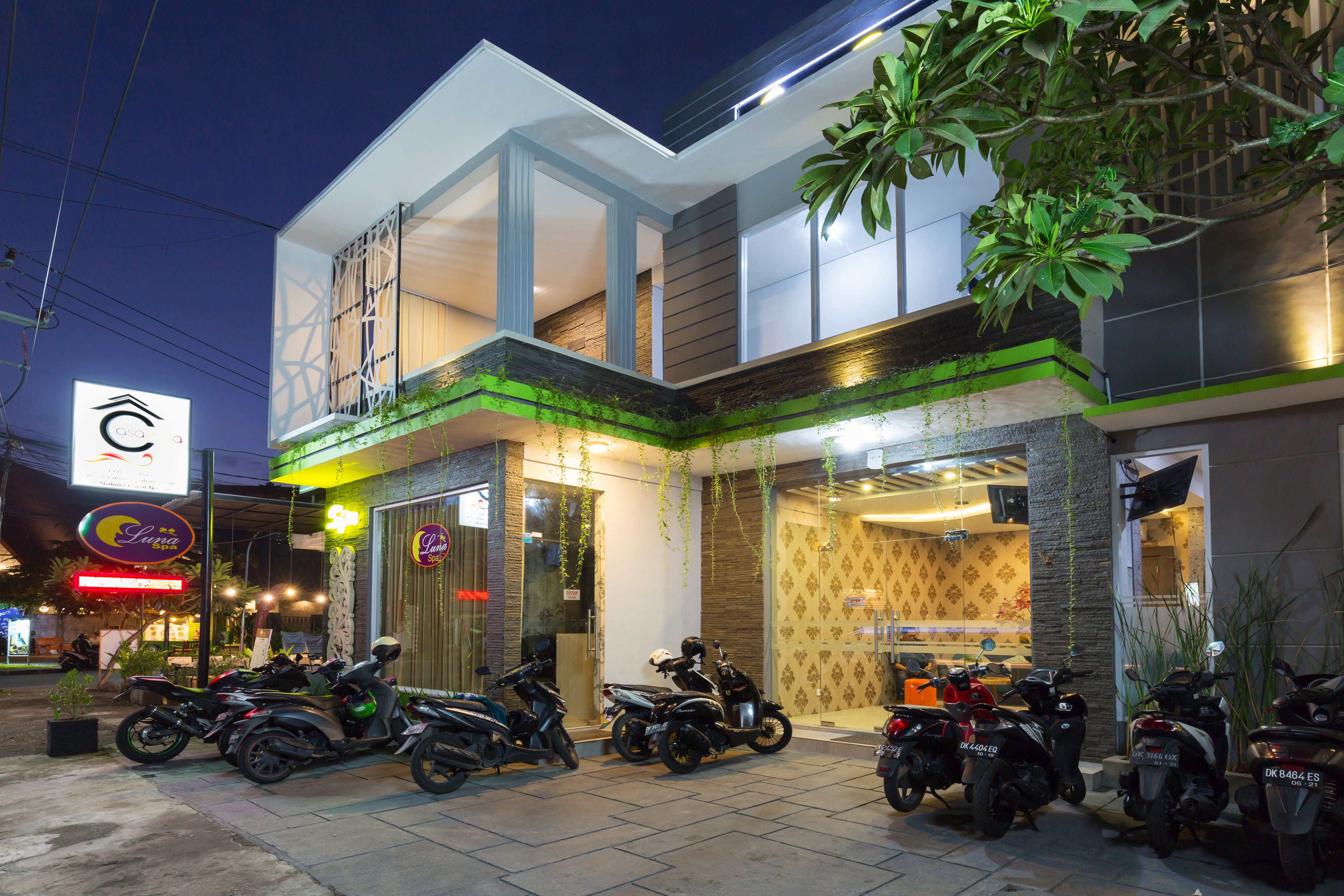 A modern building with a glass entrance, several motorcycles parked outside, and a sign with a logo.