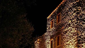 A stone building with a rustic exterior, illuminated by warm lighting. - Liotrivi Historical Mansion & Hotel (Monemvasia)