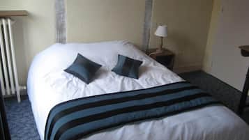 Een hotelkamer met een groot bed, twee kussens, een bedlampje en een radiator.