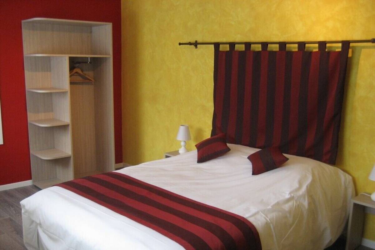 Un lit avec une couvre-lit à rayures, une armoire et une table de chevet avec une lampe.
