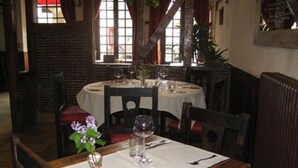 A dining area with a round table set for two, featuring a white tablecloth, wine glasses, and cutlery.