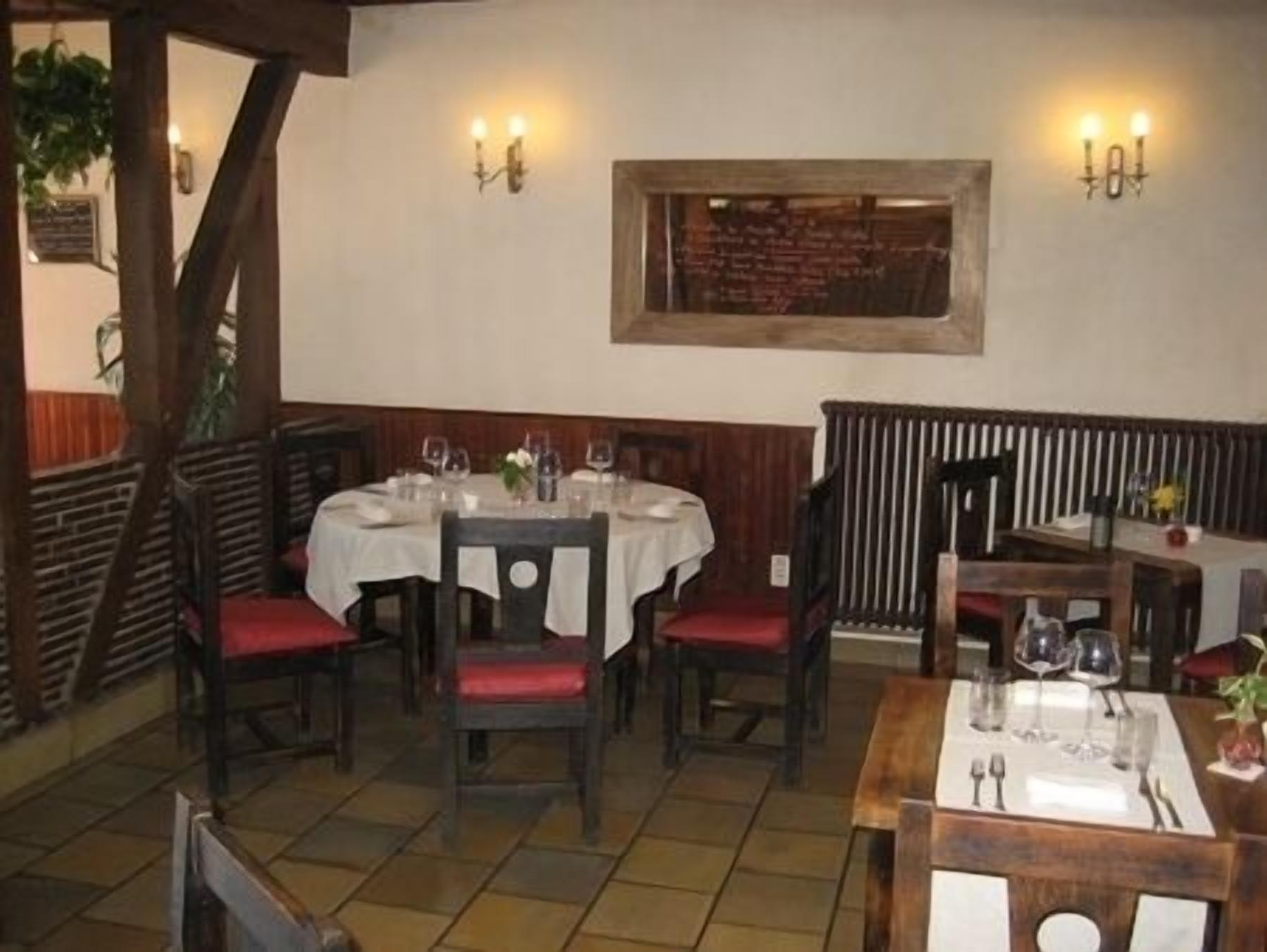 A restaurant with round tables, red cushioned chairs, and a wooden floor.