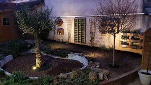 A garden with a tree, a wooden fence, and a planter with plants.