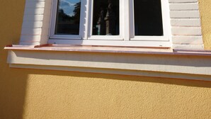A window with a decorative white frame and a triangular pediment. - Hotel Garni Rambousek (Prague)