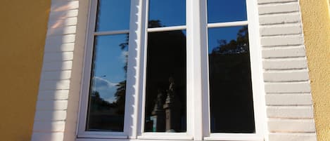 Una ventana con un marco blanco decorativo y un frontón triangular.