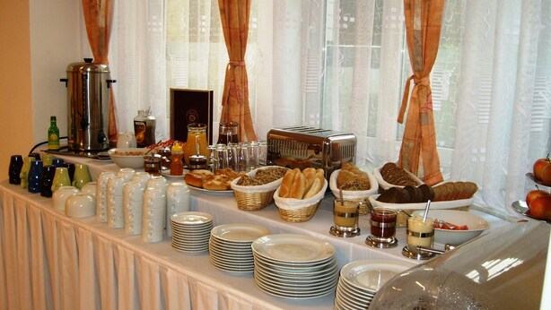 A buffet table with various food items and beverages, including bread, pastries, and condiments. - Hotel Garni Rambousek (Prague)
