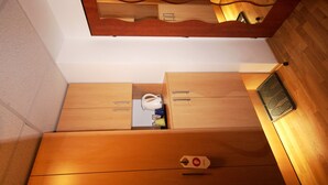A compact room with wooden cabinetry, a small table with a cup and a bottle, and a wall-mounted tray. - Hotel Garni Rambousek (Prague)