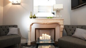 A modern living room with a fireplace, two sofas, a coffee table, and a flat-screen TV mounted on the wall. - Maison d'Anthouard (Ecully)