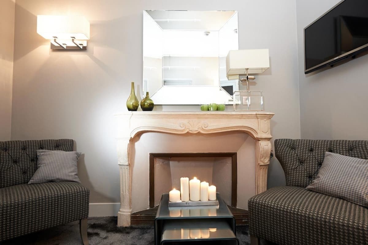 Una sala de estar moderna con chimenea, dos sofás, una mesa de centro y un televisor de pantalla plana montado en la pared.