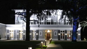 A two-story building with a central entrance, flanked by trees and illuminated by pathway lights. - Maison d'Anthouard (Ecully)
