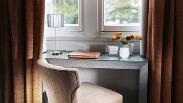 Un bureau moderne avec un ordinateur portable, une lampe et un vase rempli de fleurs.