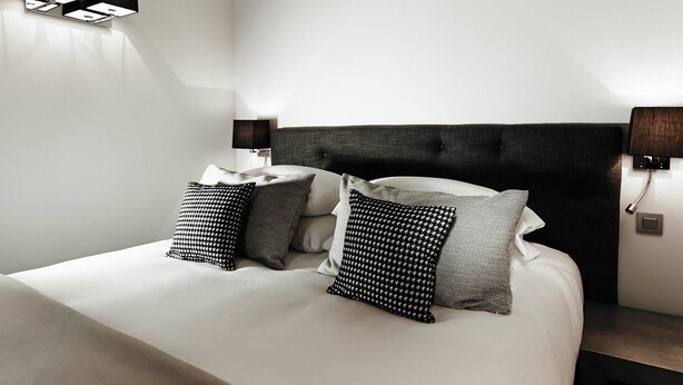 A modern hotel room with a large bed, two bedside tables, and wall-mounted lighting. - Maison d'Anthouard (Ecully)