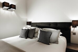 Ein modernes Hotelzimmer mit einem großen Bett, zwei Nachttischen und Wandleuchten.