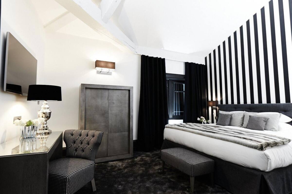 Habitación de hotel con cama, escritorio, silla, armario y televisión.