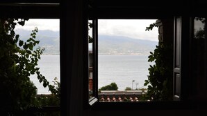 Vista a través de una ventana que muestra un cuerpo de agua y montañas al lejano.