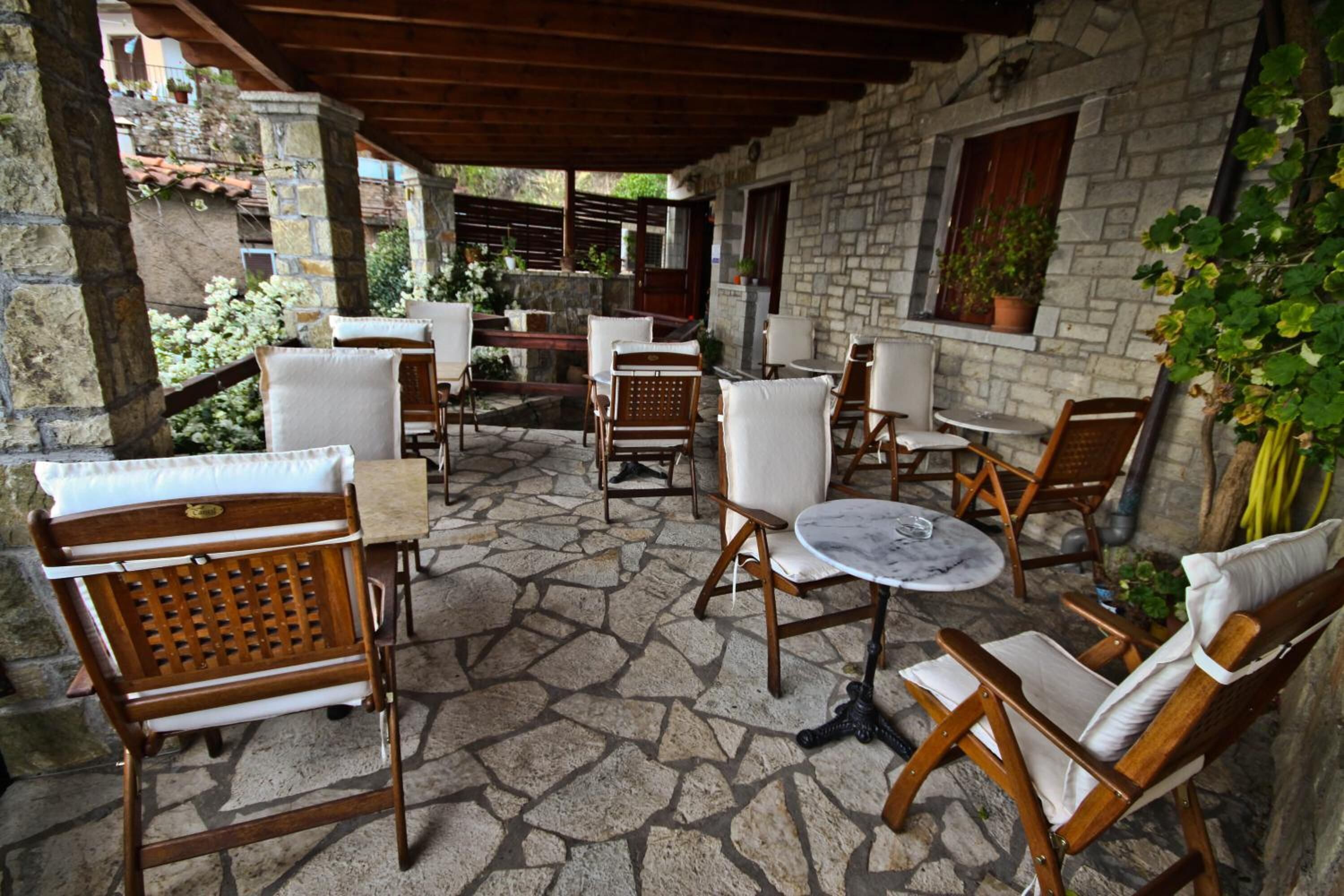 An outdoor patio with stone flooring, wooden furniture, and a stone wall.