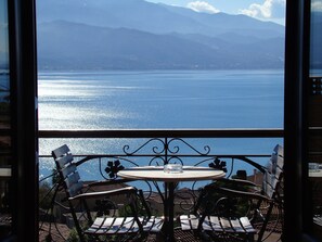 A balcony with a table and chairs overlooking a body of water and mountains. - Ilion Hotel (Nafpaktos)