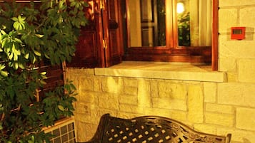 A bench and table set outside a building with a window and a potted plant.