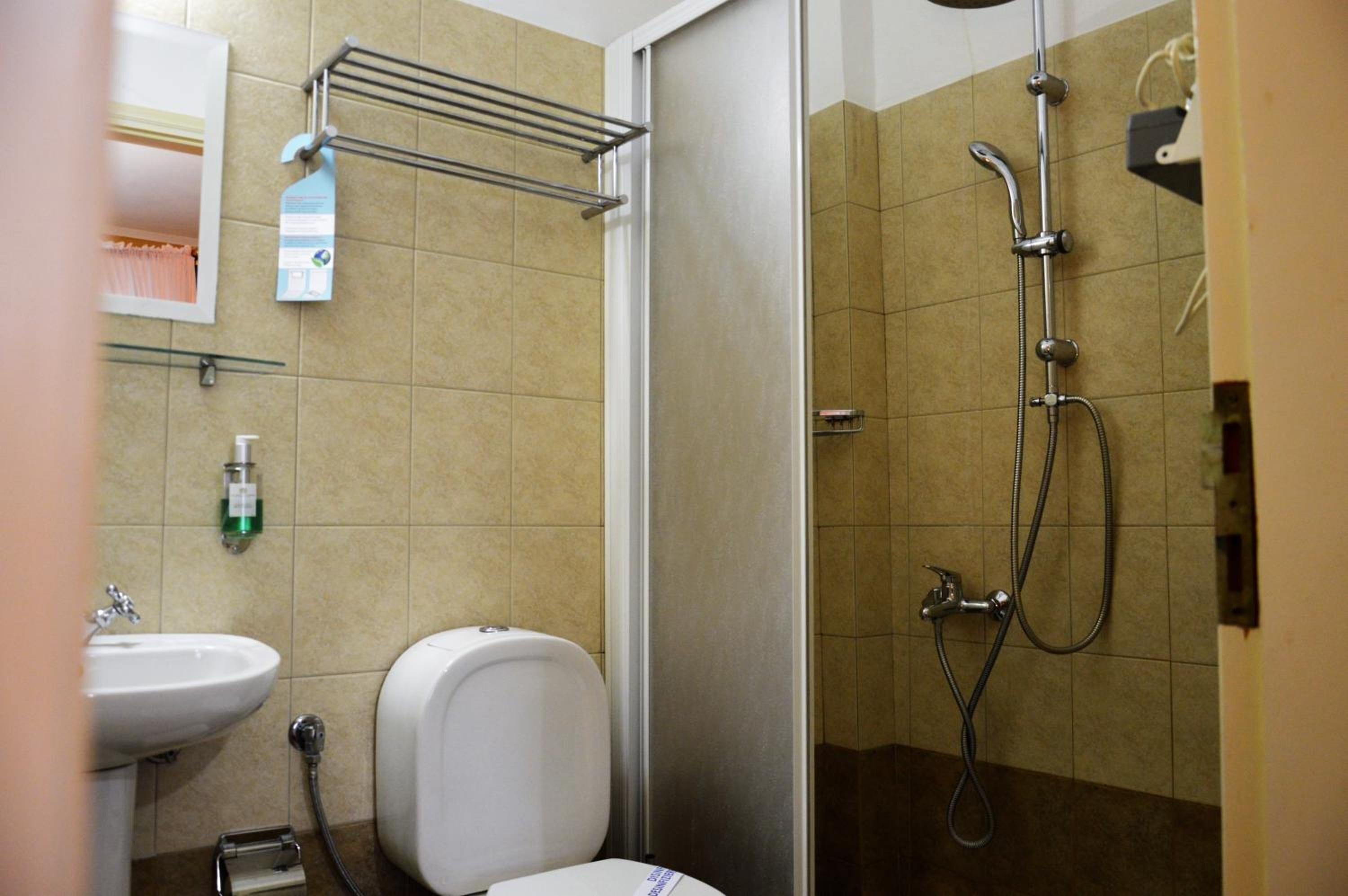 A bathroom with a shower, sink, toilet, and towel rack.