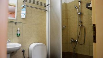 A bathroom with a shower, sink, toilet, and towel rack.