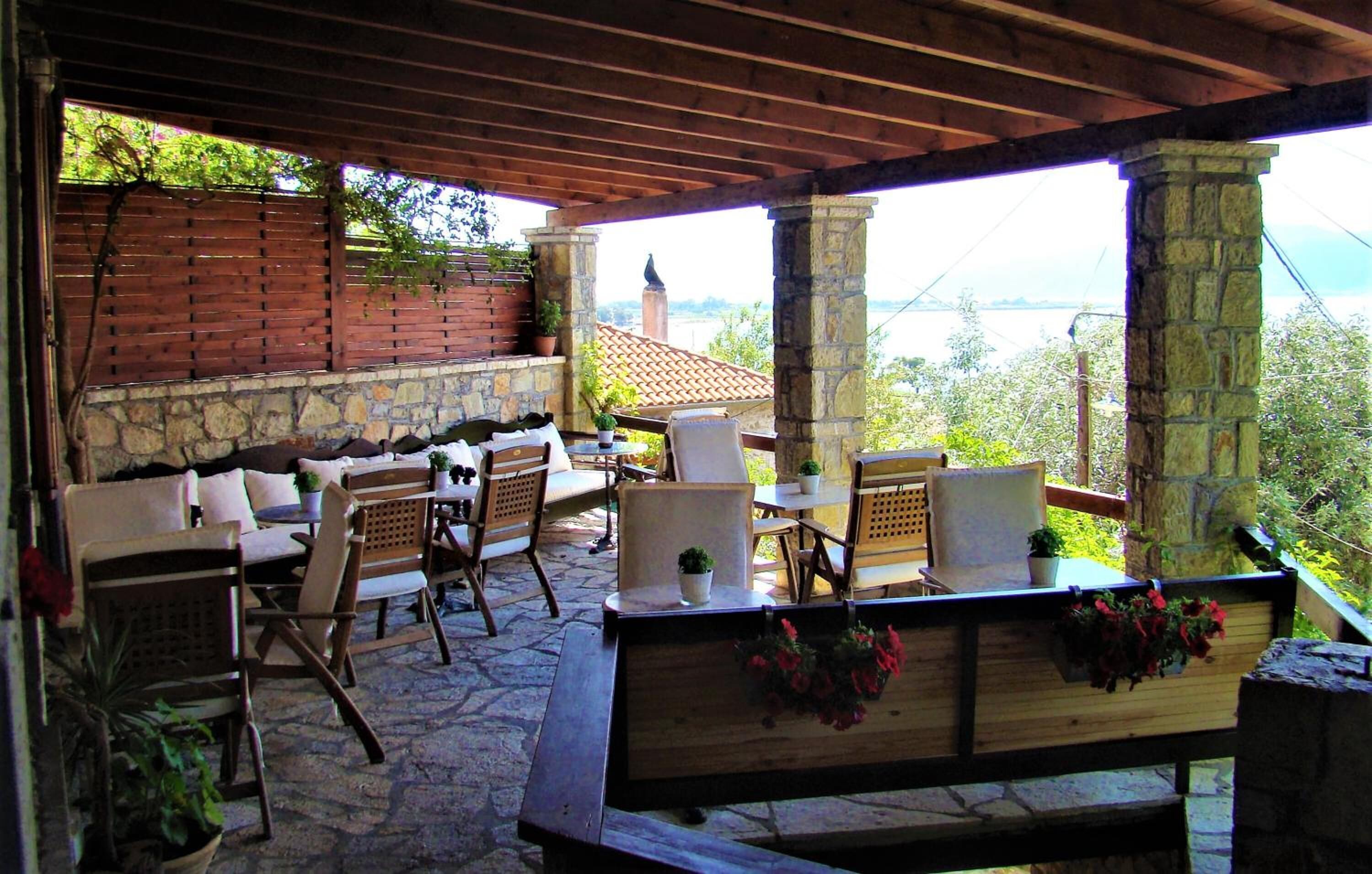 An outdoor patio with stone flooring, wooden furniture, and potted plants.