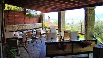 Eine Terrasse im Freien mit Steinboden, Holzmöbeln und Blumentöpfen.