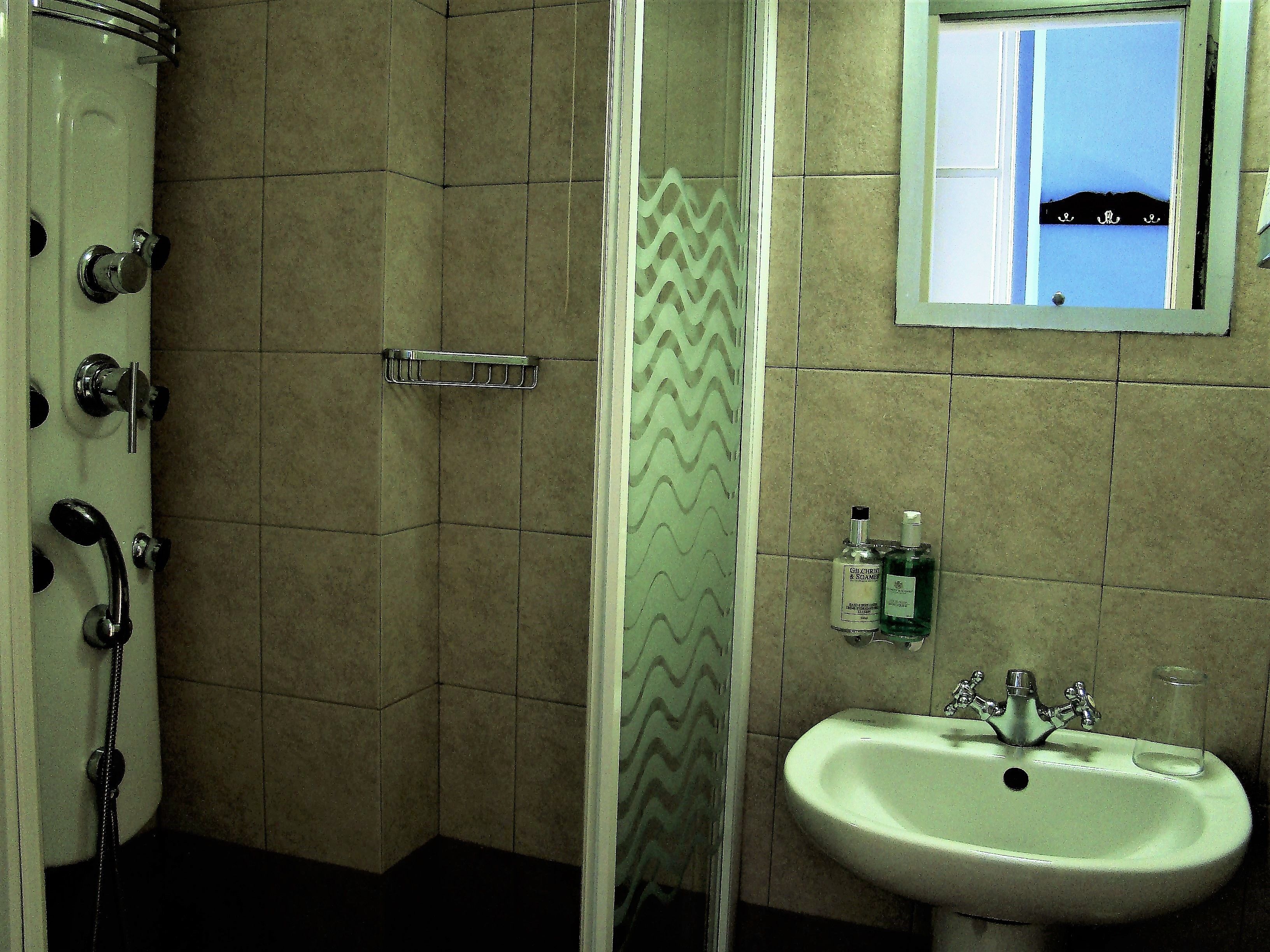 A bathroom with a shower, a sink, and a mirror.